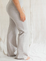 A person wearing light heather Flax gray Blondie Juniper pant, shown from the waist down against a draped white fabric backdrop.