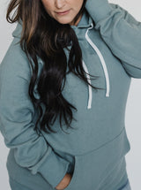 Close up view of Brunette wearing Blondie Classic Forest Hoodie in Trooper Green