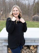 woman holding the collar of her blondie apparel cross front sweater in black